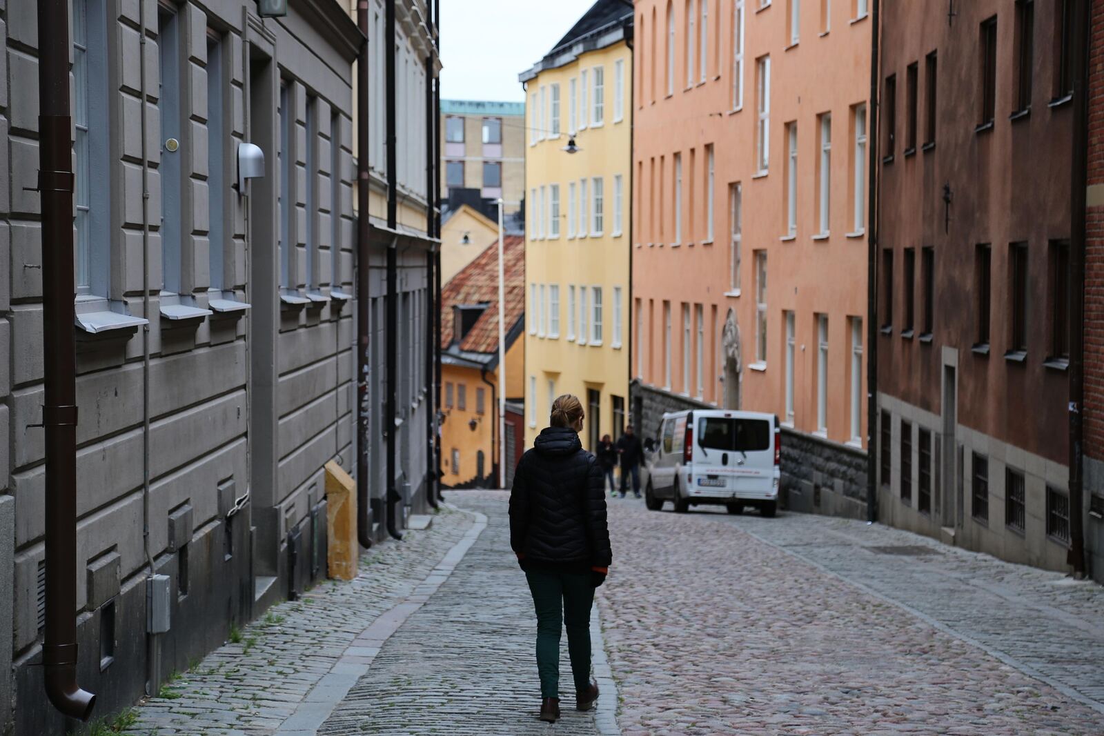 Person som går uppför en kullerstensgata mellan bostadshus